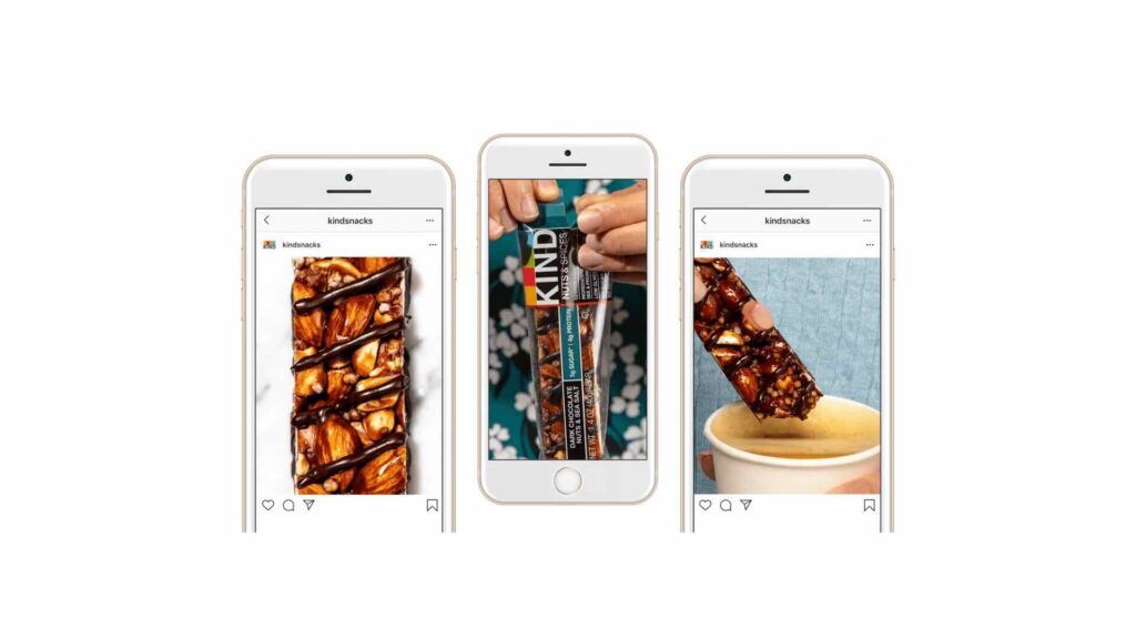An advertisement featuring three smartphones displaying Kind snack bars on their screens, with the center phone showing a hand holding a Kind bar and highlighting its wholesome ingredients. Perfect for health-savvy consumers seeking flavor and nutrition in an on-the-go snack.