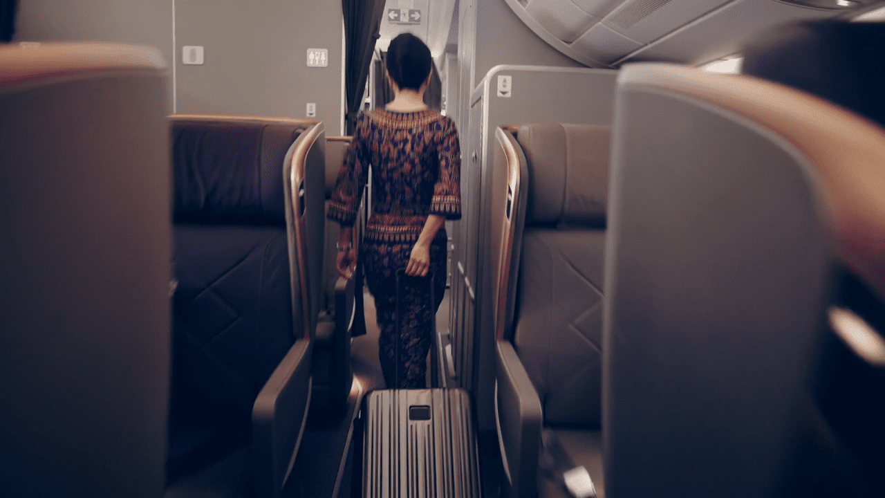 A flight attendant walks down the aisle of a Singapore Airlines Airbus A350-900 ultra-long-range aircraft, ensuring that travelers enjoy a non-stop travel experience from New York to Singapore. The luxury business class service and onboard dining options cater exceptionally well to both business and leisure travelers.